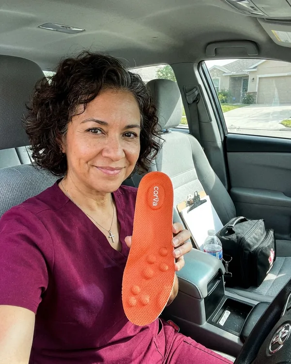 Tracy M., home health aide, holding up a CloudStep insole in her car between patient visits