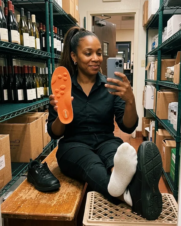 Monica R., waitress, holding up a CloudStep insole in the restaurant stockroom on her break